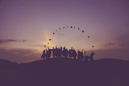 Graduates throwing their caps in the air at sunset.