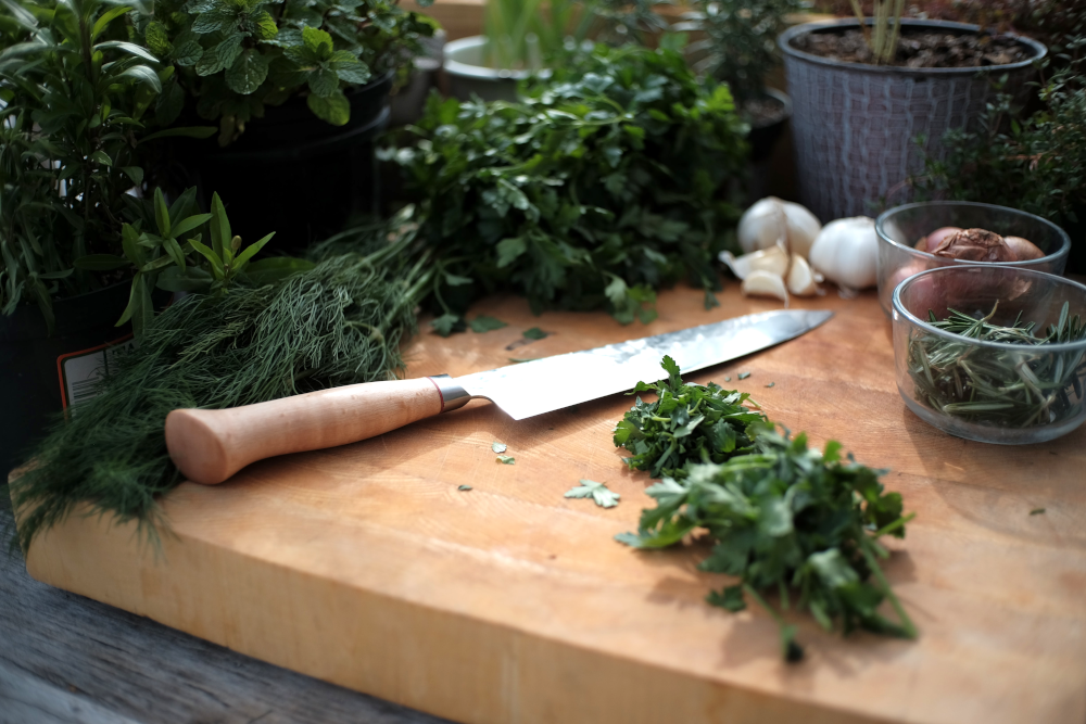 fresh herbs being chopped on a cutting board