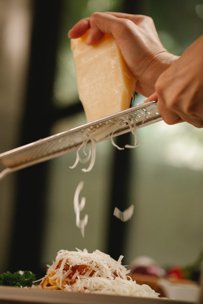 Fresh parmesan being grated onto pasta.